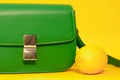 stylish little green purse or handbag on yellow background with a lemon nearby. Product composition photography. bag and Royalty Free Stock Photo