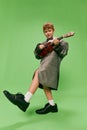 Stylish little school age boy in huge oversize retro style clothes and big male shoes posing with ukulele guitar Royalty Free Stock Photo