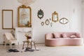 Stylish living room interior in classic or vintage style with pink sofa, different mirrors on the wall Royalty Free Stock Photo