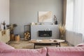 Stylish living room interior with pastel pink sofa, wooden coffee table and eco fireplace