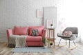 Stylish living room interior with sofa and rocking armchair near brick wall Royalty Free Stock Photo