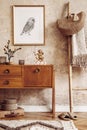 Stylish living room with vintage commode, gold mock up photo frame, wooden ladder, bag, plaid, decoration, grunge wall.