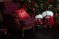 Stylish loft interior of room with Christmas fir tree and checkered armchair. Red sack santa claus with gifts near big Christmas f Royalty Free Stock Photo