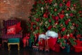 Stylish loft interior of room with Christmas fir tree and checkered armchair. Red sack santa claus with gifts near big Christmas f Royalty Free Stock Photo