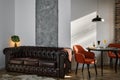 Stylish loft-style living and dining area with ebony table and red armchairs. Sunshine morning light from the window illuminates Royalty Free Stock Photo