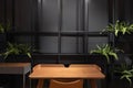 Stylish loft working corner with wood table, leather chair and artificial plant with black metal rod on the background / interior