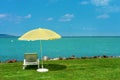 Stylish lounger plastic sunbed with yellow stripes sunshade beach umbrella on the green grass on beach at summer under open sky.