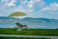 Stylish lounger plastic sunbed with yellow stripes sunshade beach umbrella on the green grass on beach at summer under open sky.