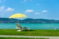 Stylish lounger plastic sunbed with yellow stripes sunshade beach umbrella on the green grass on beach at summer under open sky.