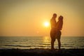 Stylish loving couple hugging each other on the beach at sunset. Man and woman in holiday honeymoon trip