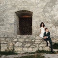 Stylish luxury bride and groom posing together near old castle wall and wooden door at sunset. amazing moment of beautiful wedding Royalty Free Stock Photo