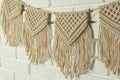 Stylish macrame hanging on white brick wall, closeup