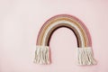 Stylish macrame rainbow decoration on pink background. Modern boho rope rainbow for baby room or simple stylish girl room. Wall