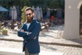 Stylish man with beard on the sunny street with crossed hands on his chest Royalty Free Stock Photo