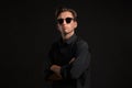 Stylish man a black shirt and sun glasses isolated over black background. Low key portrait. Royalty Free Stock Photo