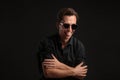 Stylish man a black shirt and sun glasses isolated over black background. Low key portrait. Royalty Free Stock Photo