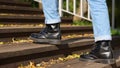 Guy in black boots going up the stairs in the park during sunny day. Leaves on the stairway. Cropped. Concept of autumn Royalty Free Stock Photo