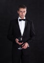 Stylish man in elegant black tuxedo with glass red wine