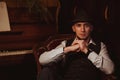 stylish man in hat is sitting in an armchair in a chic retro interior of restaurant Royalty Free Stock Photo