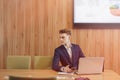 A stylish man in a jacket and shirt sits at the desk with his colleagues and works with documents at office Royalty Free Stock Photo