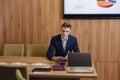 A stylish man in a jacket and shirt sits at the desk with his colleagues and works with documents at office Royalty Free Stock Photo