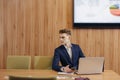 A stylish man in a jacket and shirt sits at the desk with his colleagues and works with documents at office Royalty Free Stock Photo