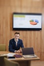 A stylish man in a jacket and shirt sits at the desk with his colleagues and works with documents at office Royalty Free Stock Photo