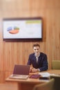 A stylish man in a jacket and shirt sits at the desk with his colleagues and works with documents at office Royalty Free Stock Photo