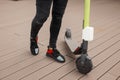 Stylish man in jeans in sneakers rides an electric scooter around the city on a summer day. Close-up of male legs Royalty Free Stock Photo