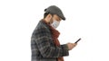 Stylish man in medical mask walking and using smart phone on whi Royalty Free Stock Photo