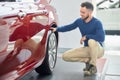 Stylish man with modern haircut squatting near luxury car. Royalty Free Stock Photo