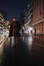 Stylish businessman in the rain, smoking a cigarette while waiting for a taxi in the busy city. Royalty Free Stock Photo