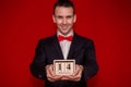 Stylish man in suit hold wooden calendar, set on 14 February with red background, focus on calendar
