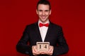 Stylish man in suit hold wooden calendar, set on 14 February with red background