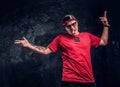 Stylish man with a tattoo on his hand dressed in a hip-hop style, having fun and posing for a camera. Studio photo Royalty Free Stock Photo