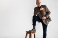 Stylish mature man putting leg on chair while standing and holding glasses Royalty Free Stock Photo