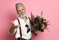 Stylish middle-aged bearded man with a modern haircut and fashionably dressed holds a bouquet of flowers. Royalty Free Stock Photo
