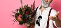 Stylish middle-aged bearded man with a modern haircut and fashionably dressed holds a bouquet of flowers. Royalty Free Stock Photo
