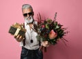 Stylish middle-aged bearded man with a modern haircut, sunglasses and fashionably dressed holds a bouquet of flowers Royalty Free Stock Photo