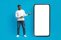 Stylish millennial african american guy posing by huge smartphone Royalty Free Stock Photo