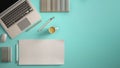 Stylish minimal office table desk. Workspace with laptop, notebook, pencils, coffee cup and sample color palette on pastel turquoi