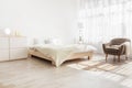 Stylish minimalist contemporary boho home interior. Double bed with pillows and blanket, furniture, lamp, armchair