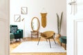 Stylish and minimalist interior of living room with design gold armchair, lamp, poster frames. dressing table with mirror, plants Royalty Free Stock Photo