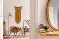 Stylish and minimalist interior of living room with design gold armchair, lamp, poster frames. dressing table with mirror, plants.