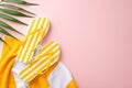 Stylish minimalistic beach vacation concept. Top view flat lay of yellow striped flip-flops, towel, green palm leaves on pastel Royalty Free Stock Photo