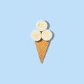 Stylish mockup with banana slices in an ice cream waffle cone on a pastel blue background. Creative healthy food concept