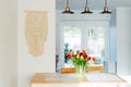 Stylish and modern boho, scandi interior of open space white kitchen with tulip flowers in vase on the wooden kitchen