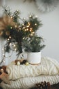 Stylish modern cup with fir branches on cozy sweater with ornaments and pine cones on background of warm lights and sweden star in