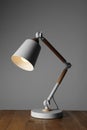 Stylish modern desk lamp on wooden table against grey background