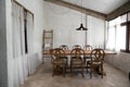 Stylish modern loft dining area with natural light scene and bare concrete wall with natural wood table and chairs setting /